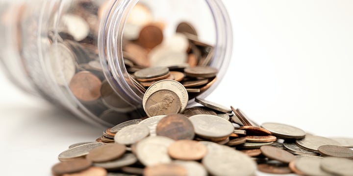 Penny jar laid on its side with pennies spilled out.