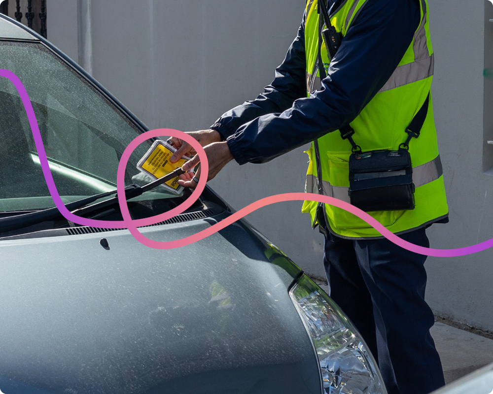 Image of a traffic warden putting a ticket on a car.