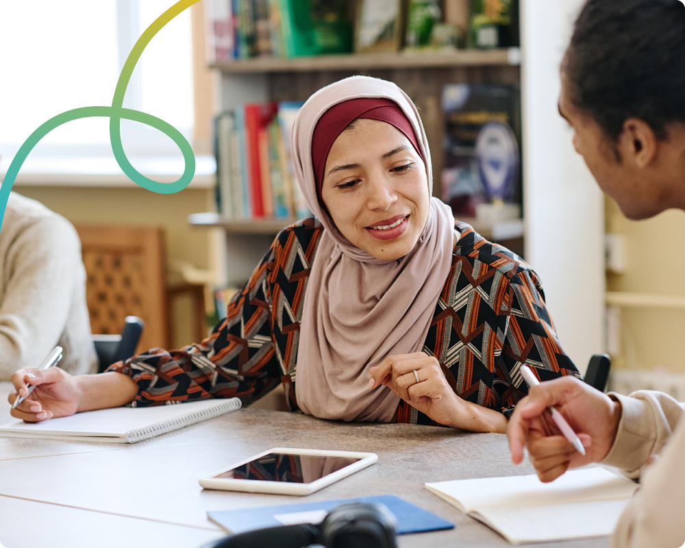 Image of a woman wearing a hijab, writing, making some notes