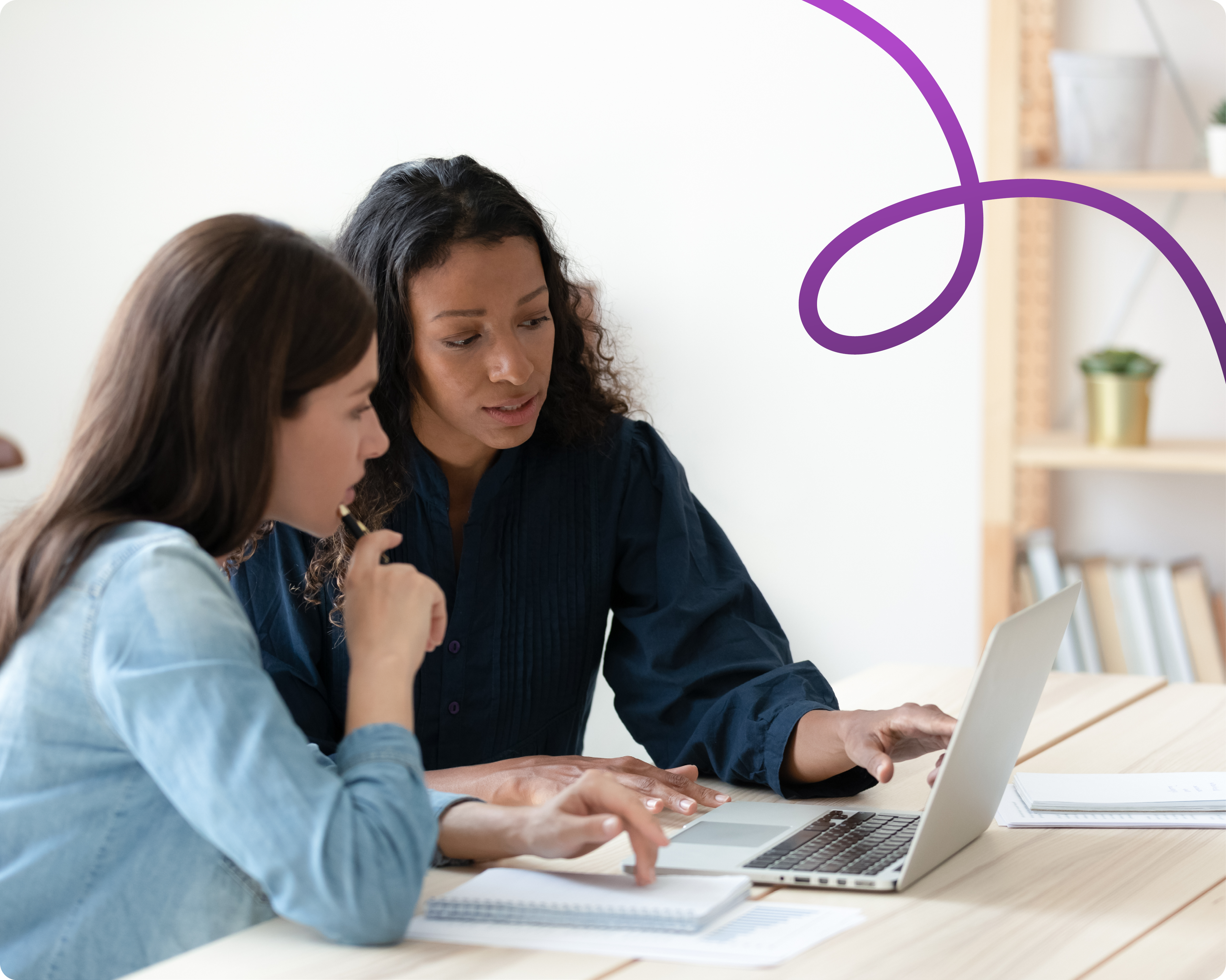 Image of two women sat infront of a laptop working. there is a purple connecting line in the top right corner.