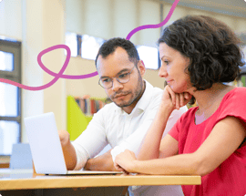 Image of a man and woman sat at a desk looking at a laptop