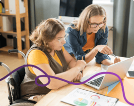 Image of a young woman and her mum sat at a desk looking at a laptop