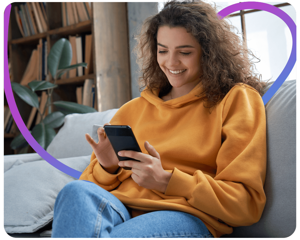 Image of a young woman sat on a sofa looking at her phone