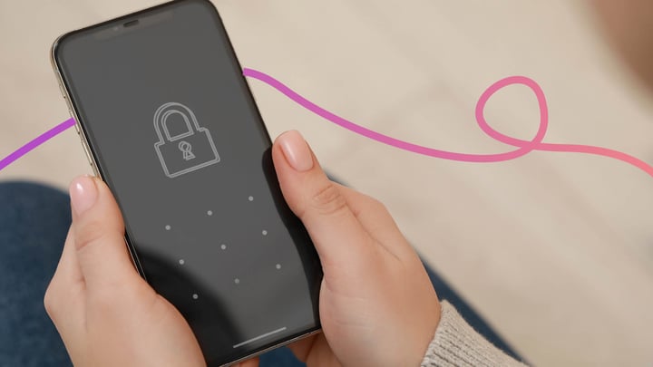 A close up of a person holding a smart phone. The screen shows a locked padlock symbol demonstrating that the person is digitally excluded.