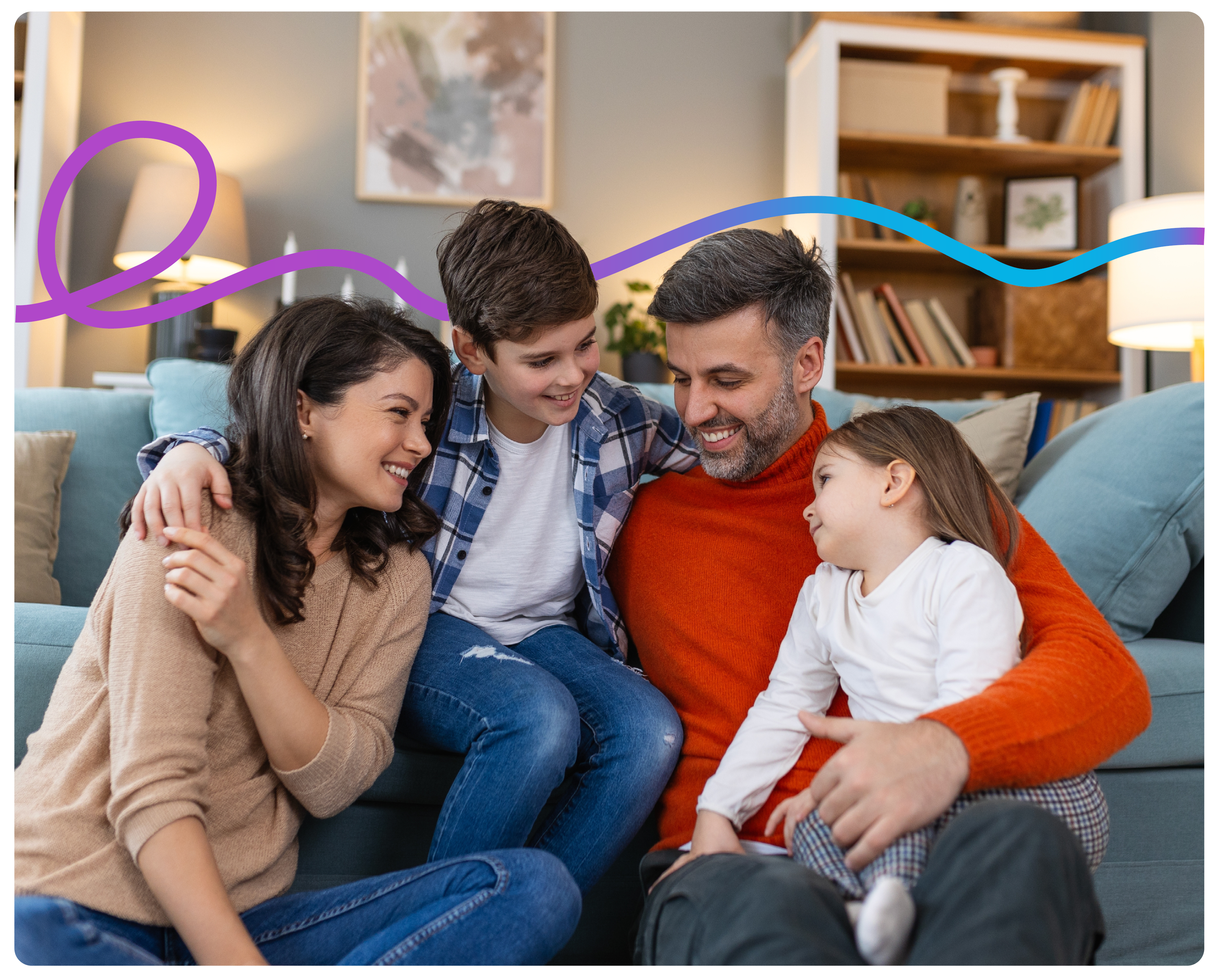 A family of four sitting in front of the sofa hugging.