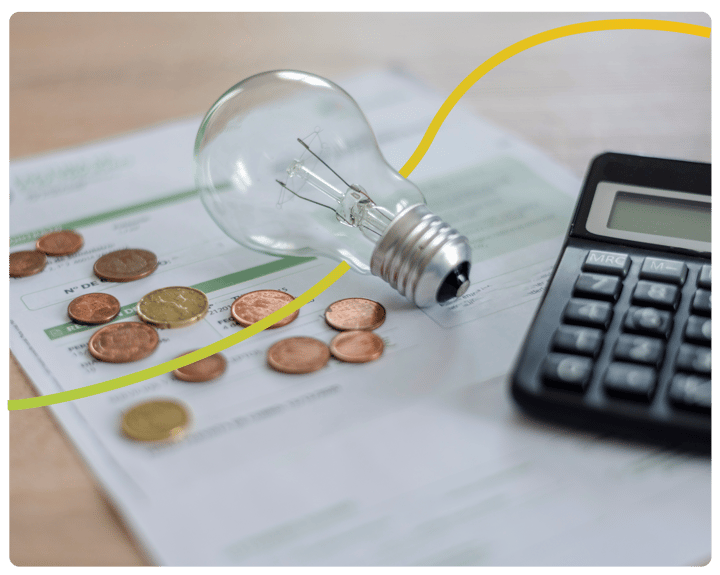 An energy bill, lightbulb, coins and a calculator on a table.
