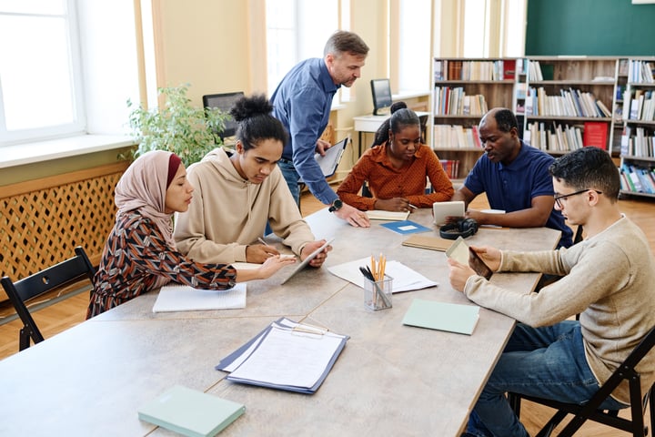 A diverse group of people being taught digital skills by a trainer