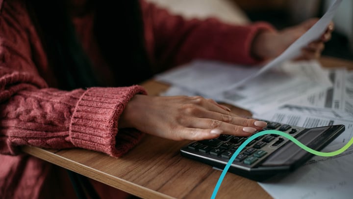 Woman's hand resting on a calculator