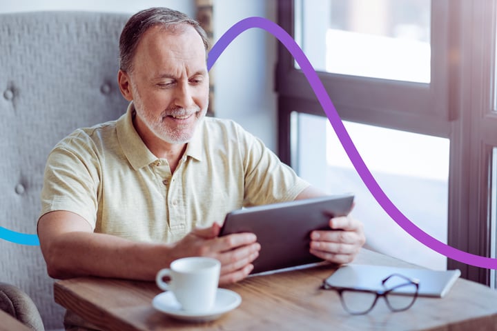 Middle-aged man sitting at a table using a tablet device.
