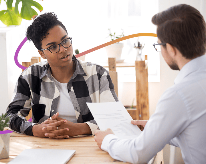 A financial adviser and customer in discussion whilst seated at a table. 