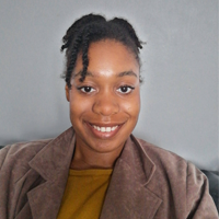 Image of a young woman (Tashaney) smiling wearing a brown jacket