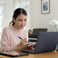 Young Asian woman on her laptop with headphones in