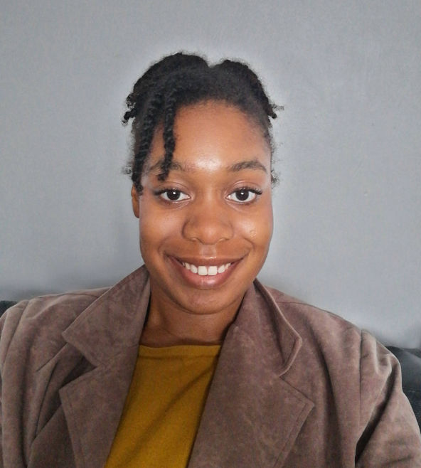 A selfie of a young woman smiling wearing brown clothing